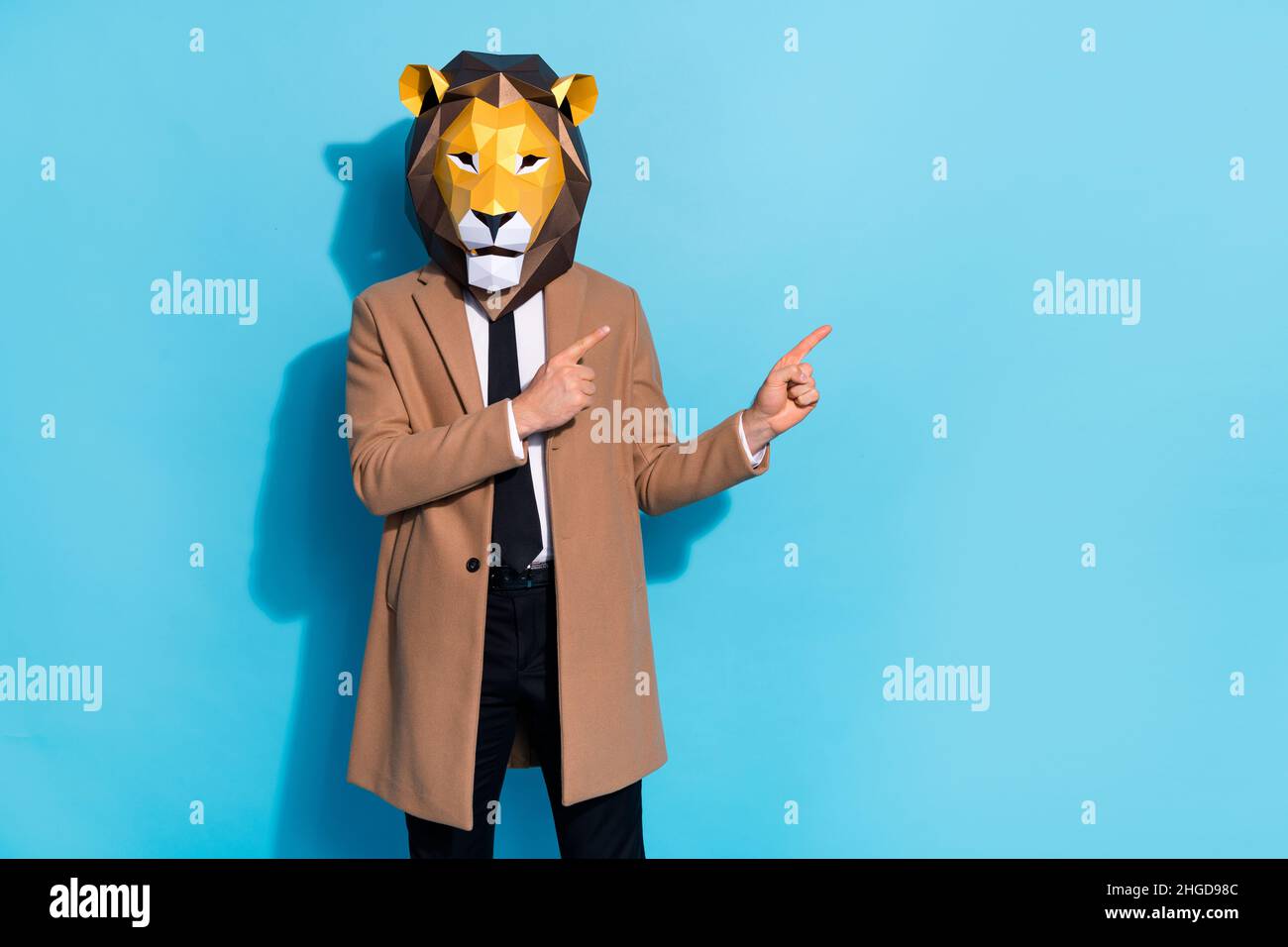 Photo of weird crazy guy lion mask point finger empty space demonstrate mardi gras ads isolated over blue color background Stock Photo