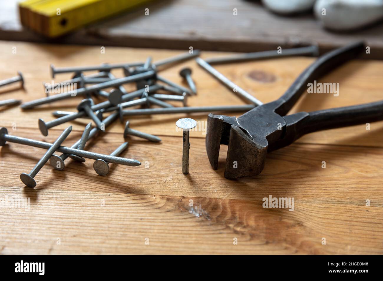 Pincers and nail stack on wood. Carpenter work bench table, closeup view, joinery workshop Stock Photo