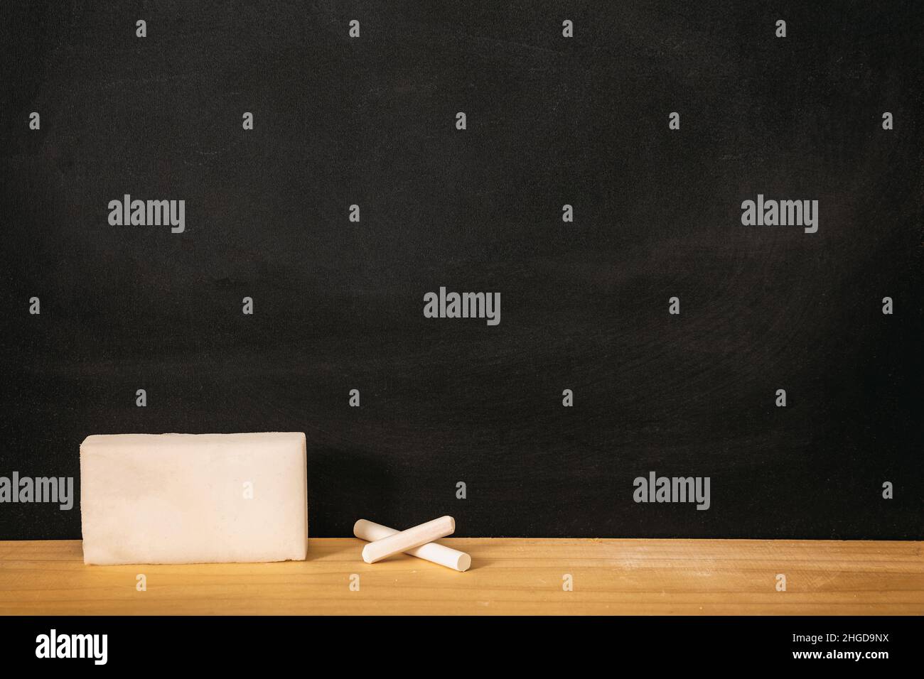 School chalkboard, blank empty black board, white chalk piece and sponge on wooden frame sill, copy space Stock Photo