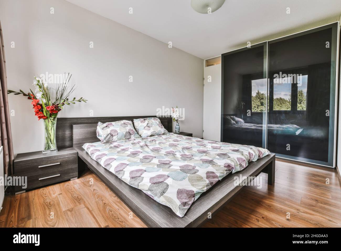 A lovely bedroom with a black bed and a vase of flowers over the