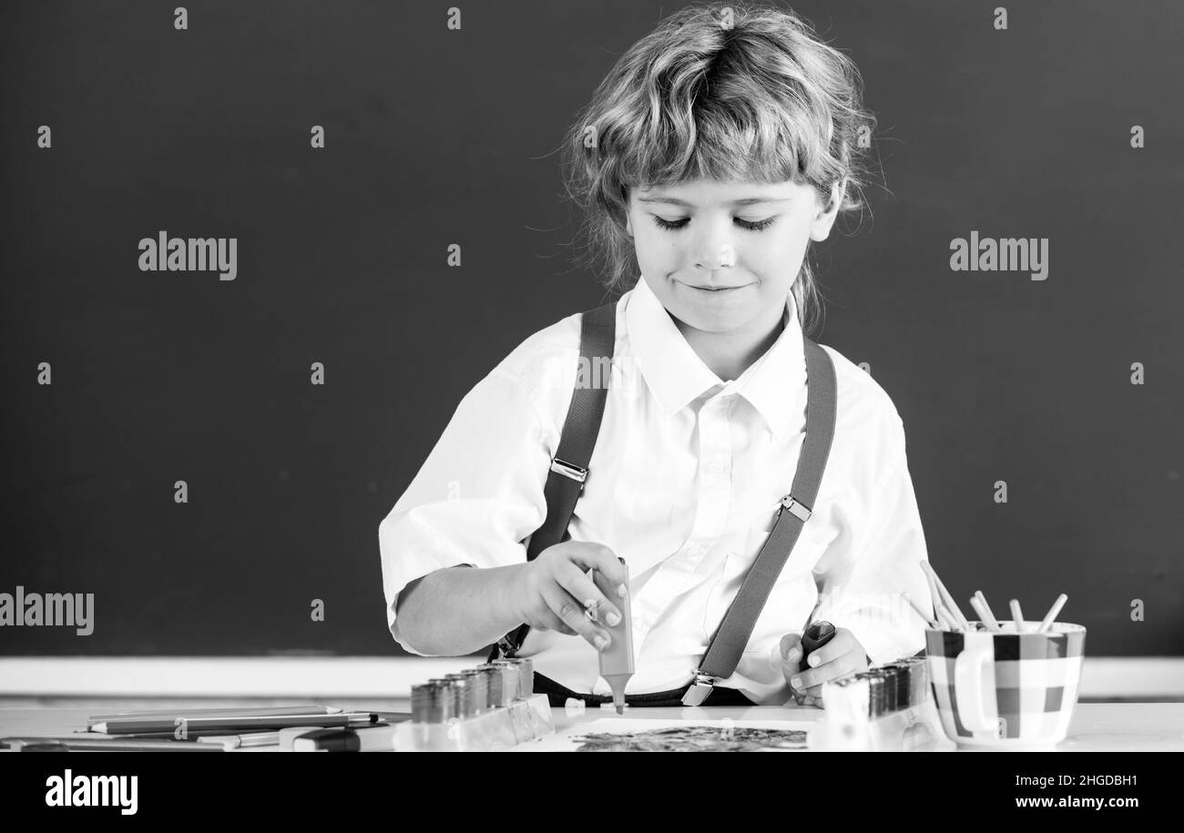 Portrait school kid boy doing art homework, holding pencil, writing. Child boy drawing on elementary school. Kids art, creativity children. Stock Photo
