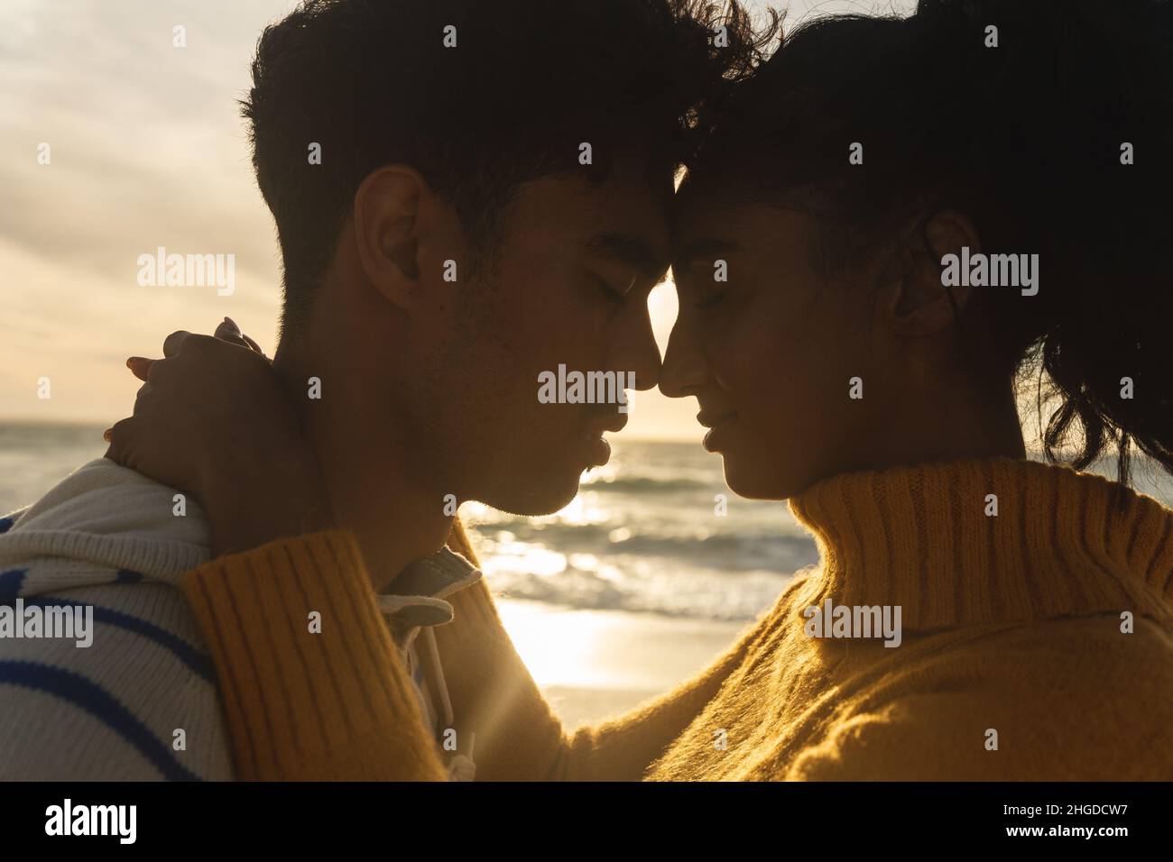 Girlfriend and boyfriend romancing while sitting face to face on beach  stock photo