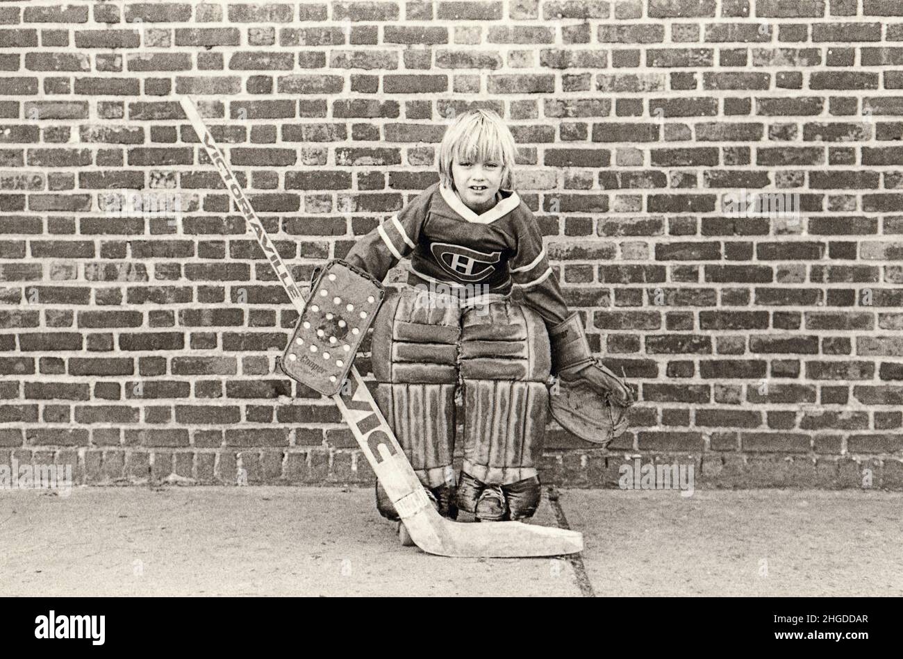 Posed portrait of a young lad who plays goalie of a roller skate street hockey team. In Brooklyn, New York, circa 1975. Stock Photo