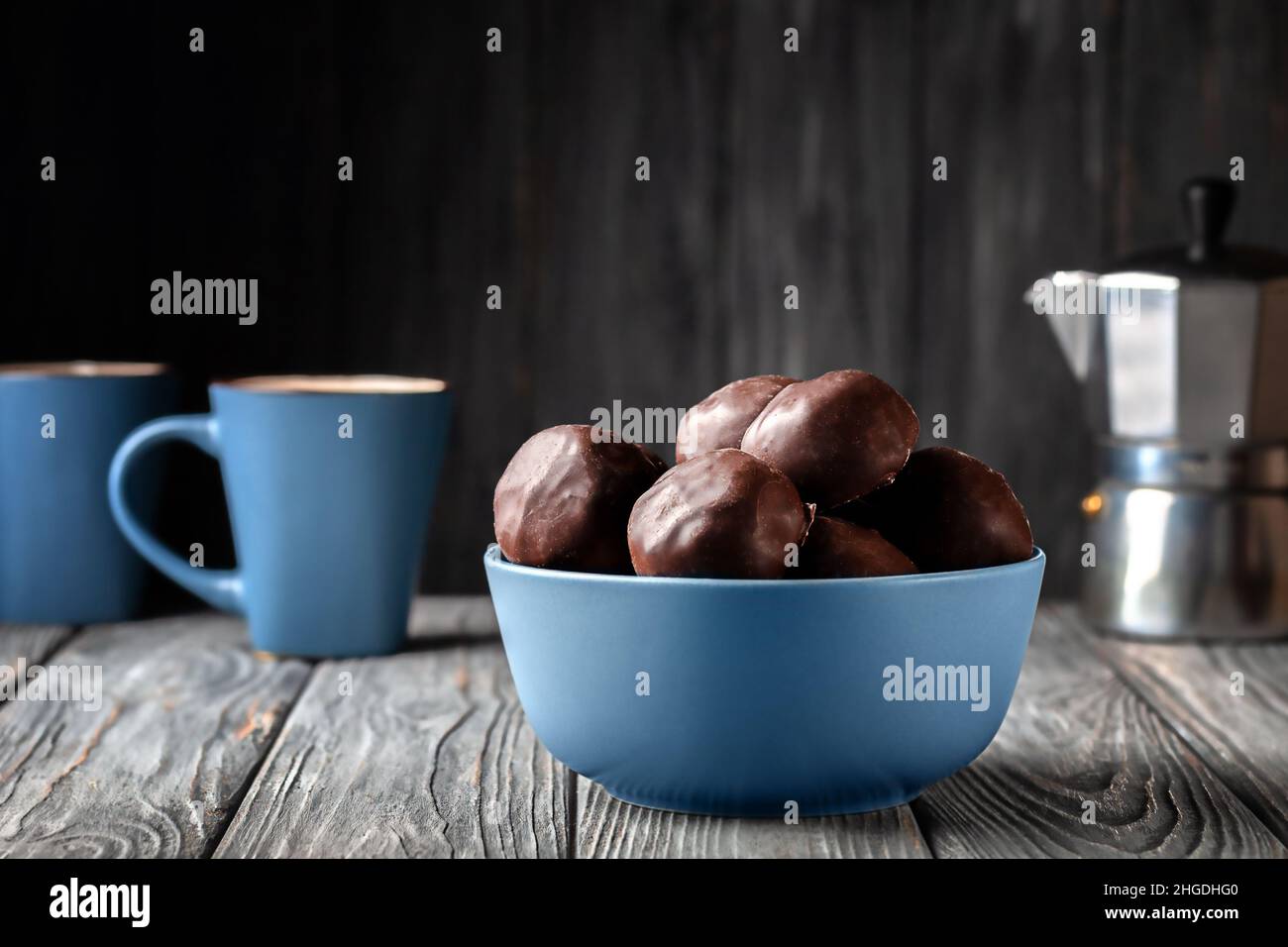 Dark chocolate balls with marshmallow filling and a cup of coffee on wooden background Stock Photo