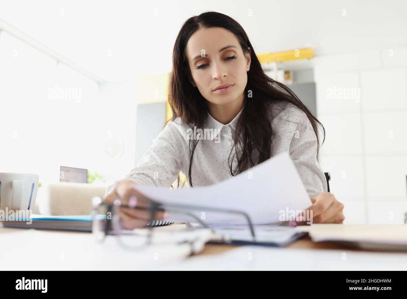 Tired overworked young woman go through paper on working place Stock Photo