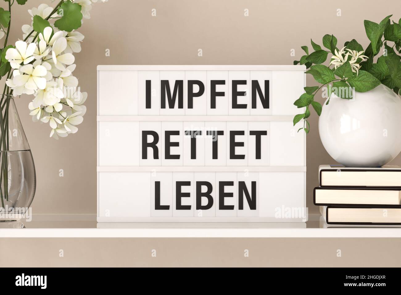 The German words 'Impfen rettet Leben' ('vaccines save lives') displayed on a lightbox standing on a shelf with flowers and books. Stock Photo