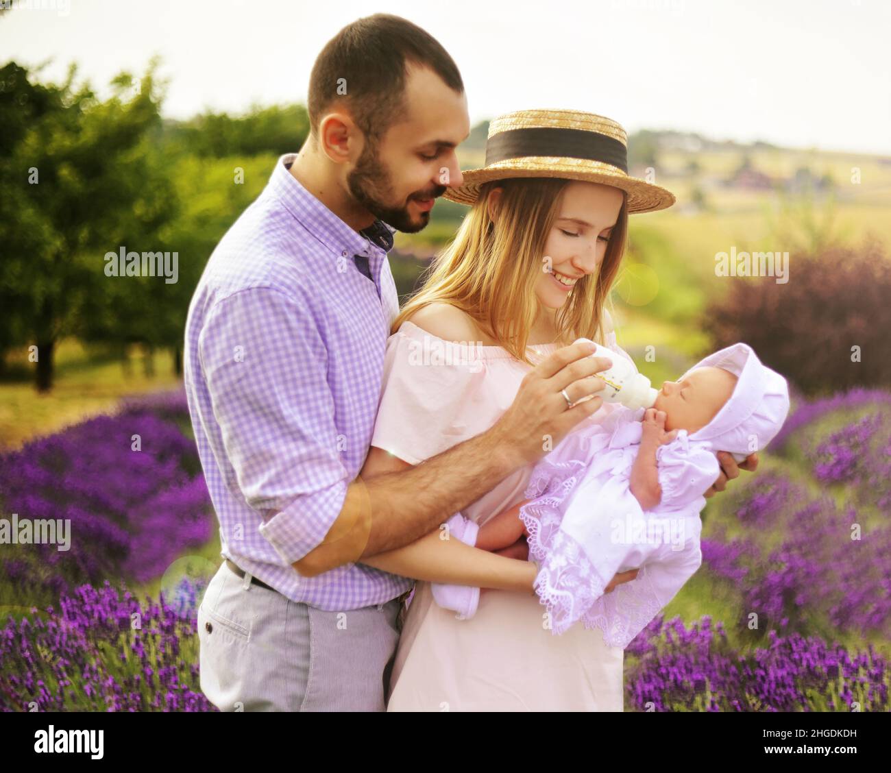 Happy caucasian family mother father and daughter are wearing white clothes are having fun in lavender field. A couple is feeding a baby from a bottl Stock Photo Alamy