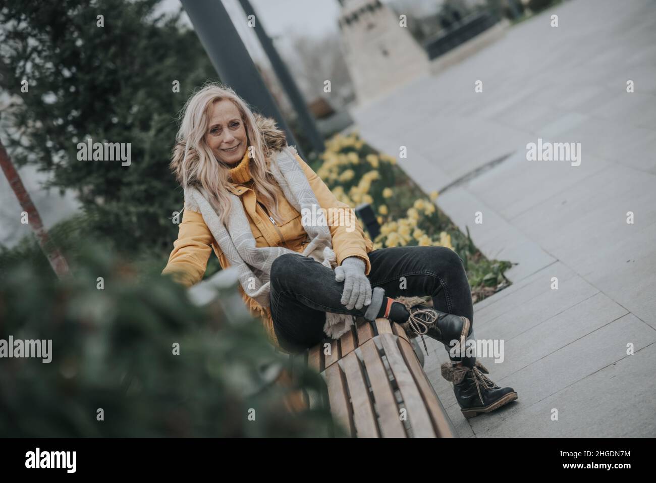 Aged pretty woman sitting on a park bench Stock Photo