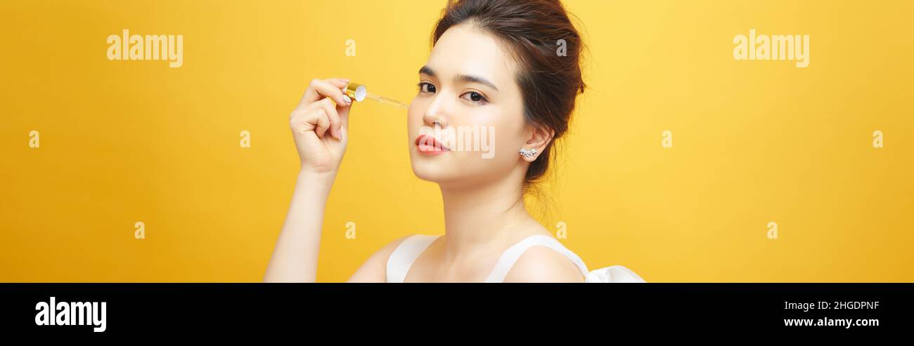 Closeup shot of cosmetic oil applying on young woman's face with pipette. Beauty therapy concept. Stock Photo
