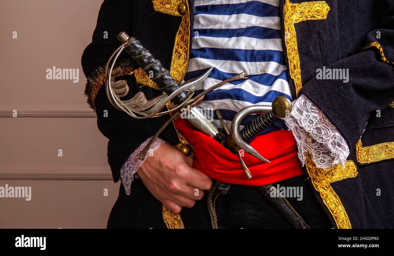 Brave armed pirate captain in a frock coat and vest with a sword and a dagger and a hook close-up Stock Photo