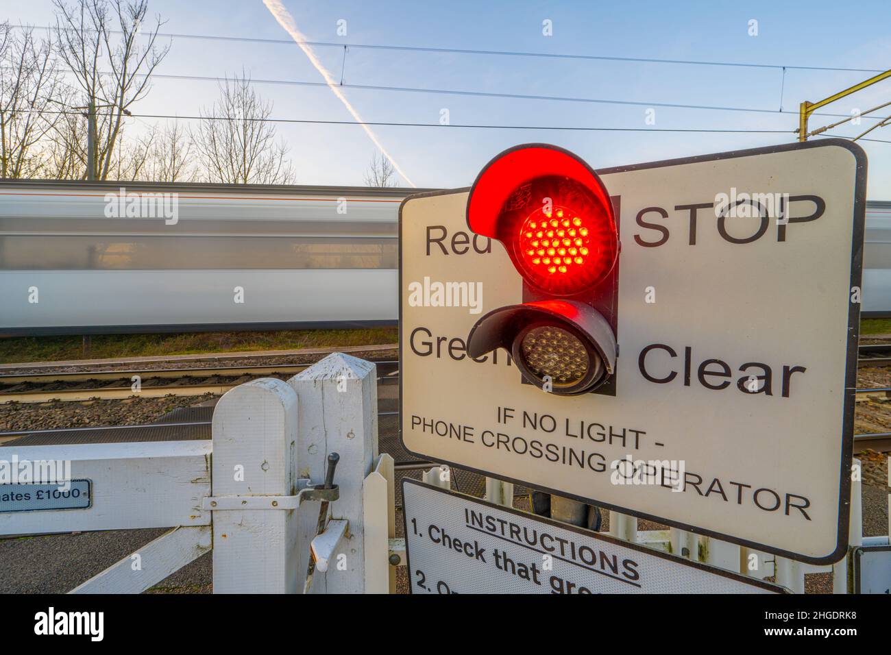 Train passing a light controlled Level crossing the the main railway line to Norfolk at Margaretting Essex Stock Photo