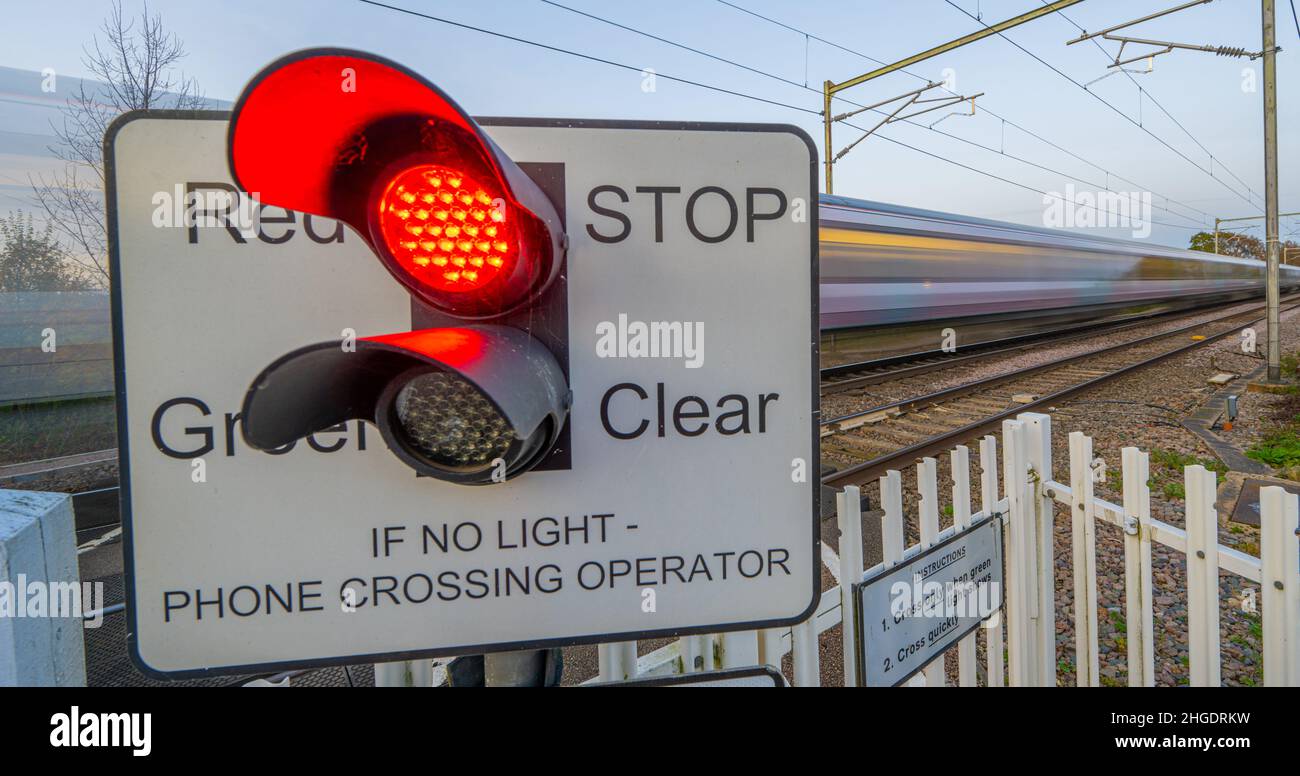 Train passing a light controlled Level crossing the the main railway line to Norfolk at Margaretting Essex Stock Photo