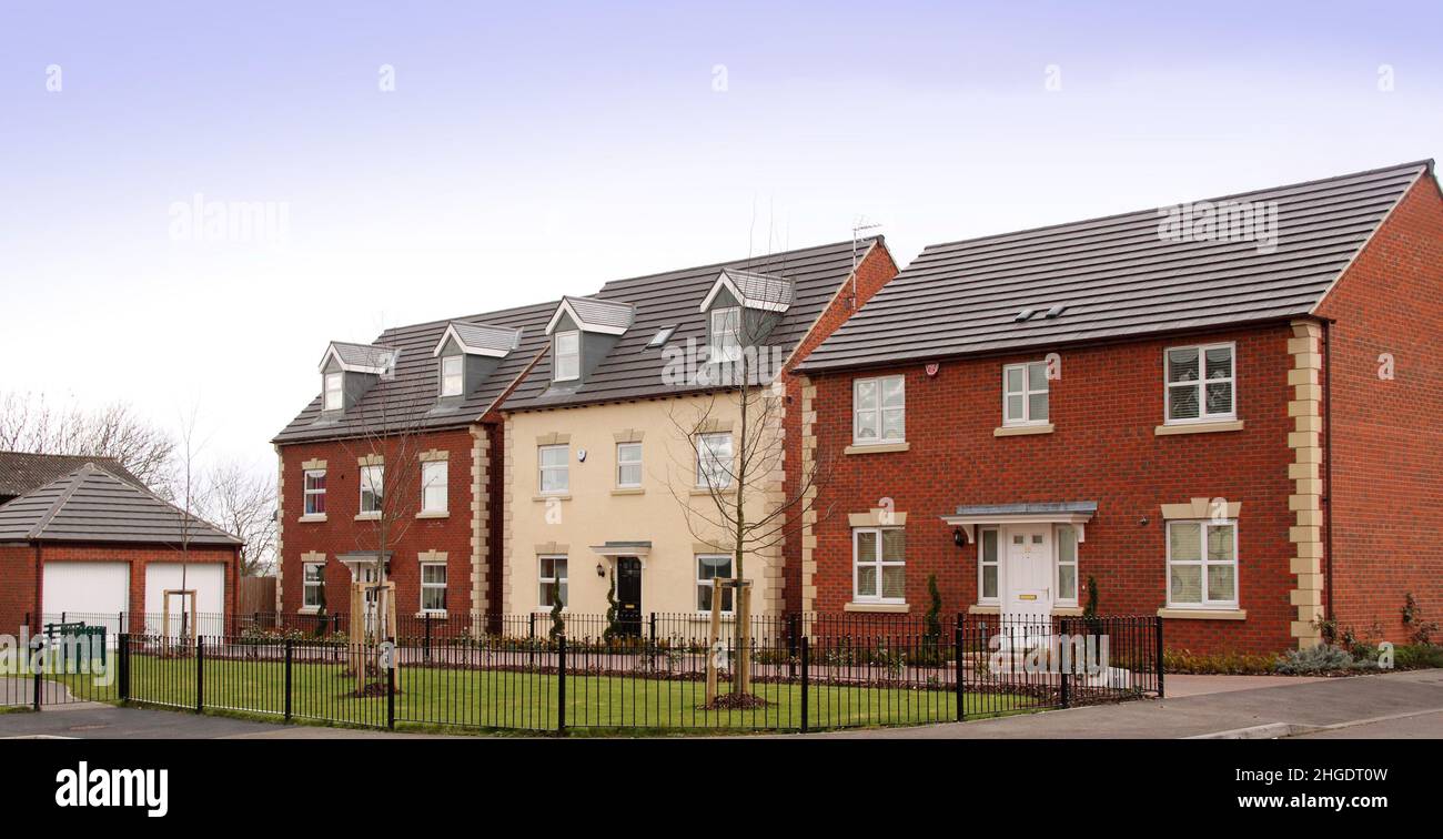 Three modern new build detached houses on a housing estate development, blue sky. Stock Photo