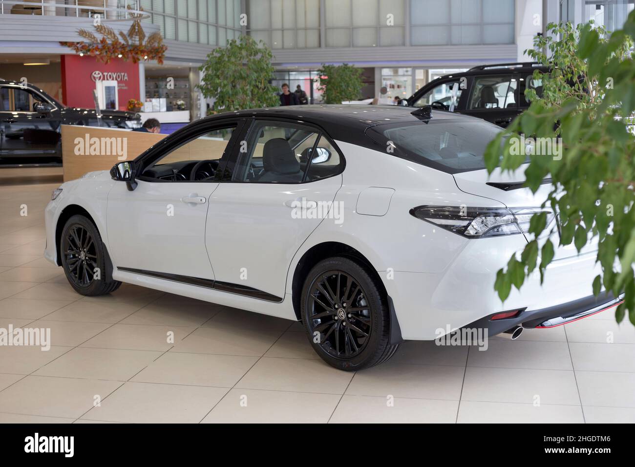 Russia, Izhevsk - September 30, 2021: Toyota showroom. New modern Toyota Camry car in dealer showroom. Side and back view. Famous world brand. Stock Photo