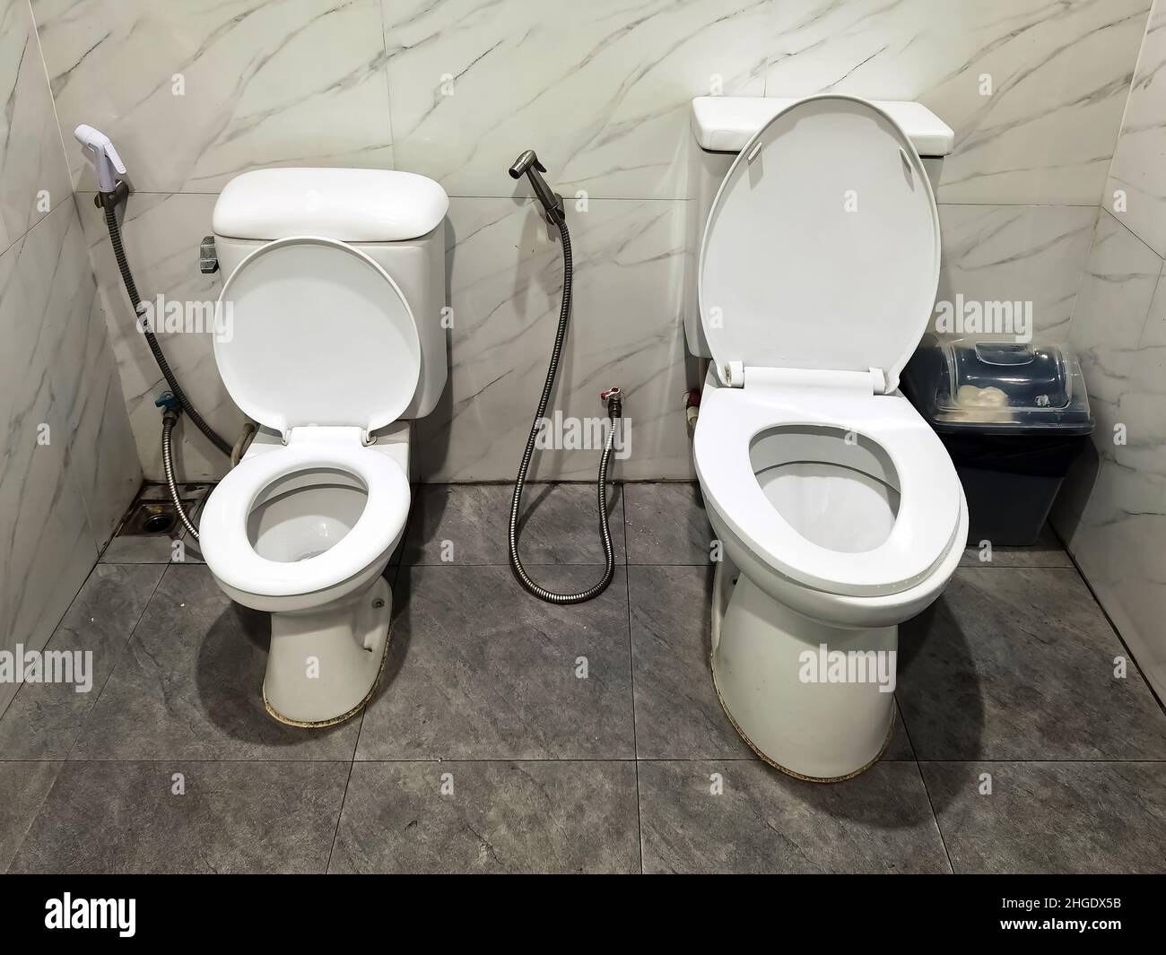 Two toilet seats installed together in one bathroom, a big one is for