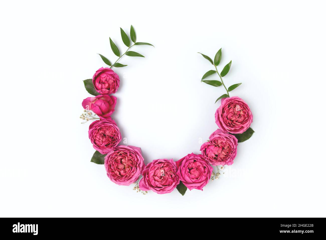 Top view of round frame made of pink rose and green leaves on a blue ...