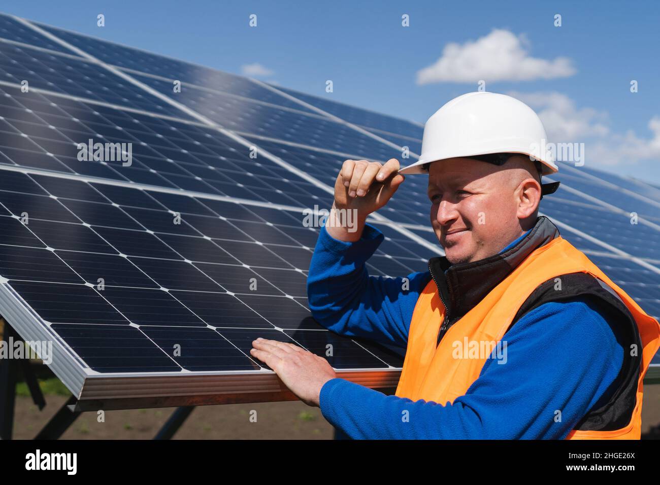 Solar farm worker leaning against the panels Stock Photo - Alamy