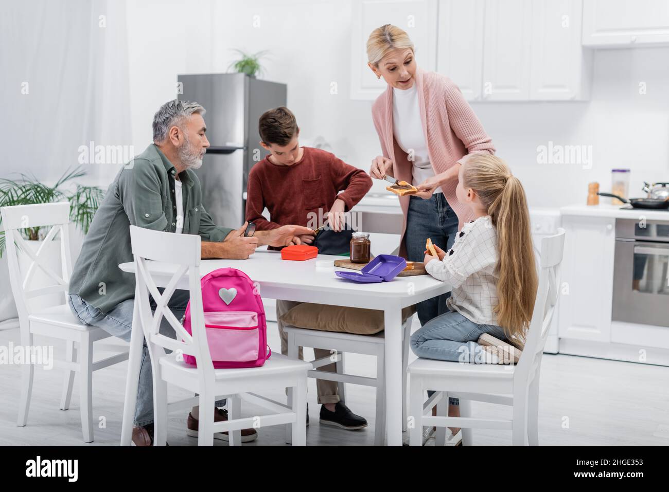 middle aged woman talking to granddaughter while preparing sandwiches in kitchen Stock Photo