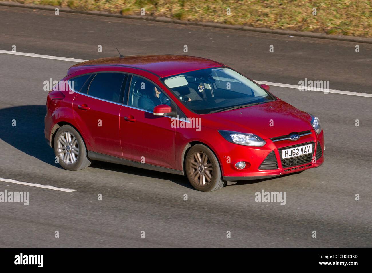 2012 red Ford Focus 998cc 6 speed manual 4dr. Vehicular traffic, moving vehicles, cars, vehicle driving on UK roads, motors, motoring on the M61 motorway highway UK road network. Stock Photo