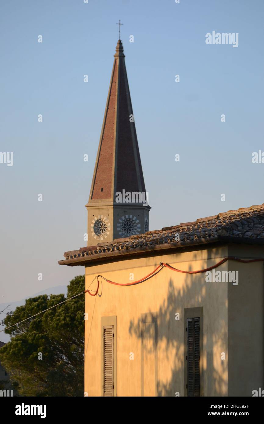 the steeple of the cathedral in neogothic style beyond a building against blue sky Stock Photo