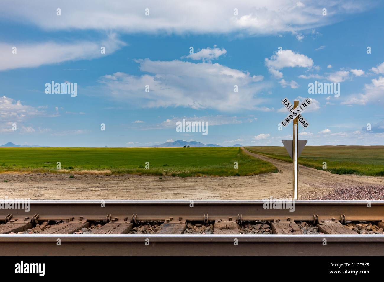 Wide lands in Montana behind rail tracks and a railroad crossing sign