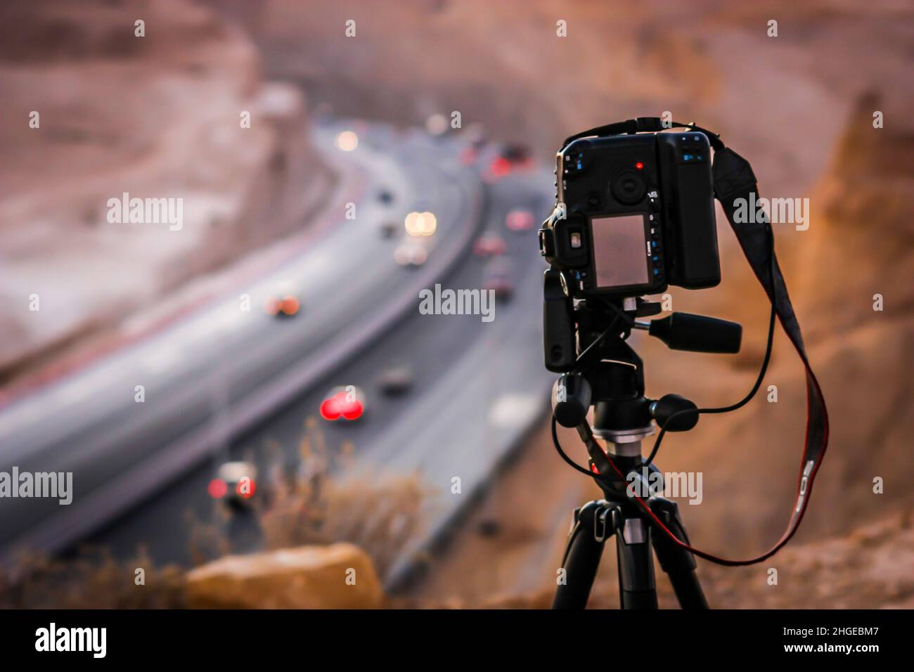 A professional DSLR camera on tripod on top of a hill capturing the