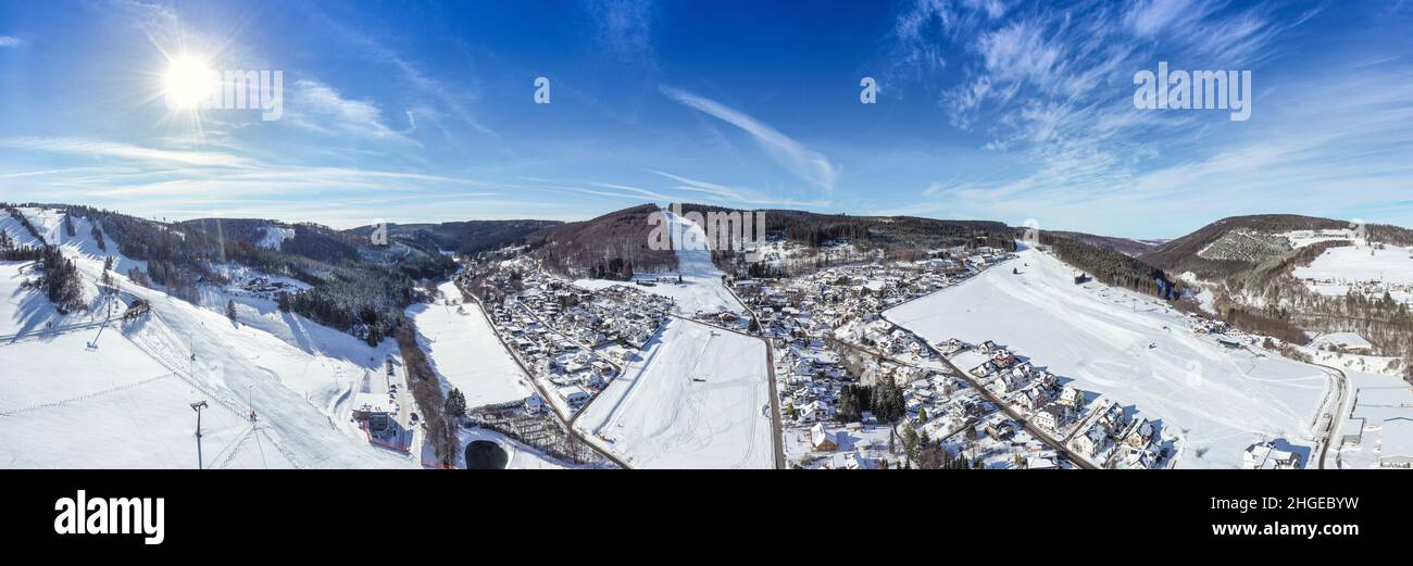 Flight over the vacation resort in Willingen in Hesse. Gastronomy and vacation houses are located next to downhill ski slopes. Wide view. Stock Photo