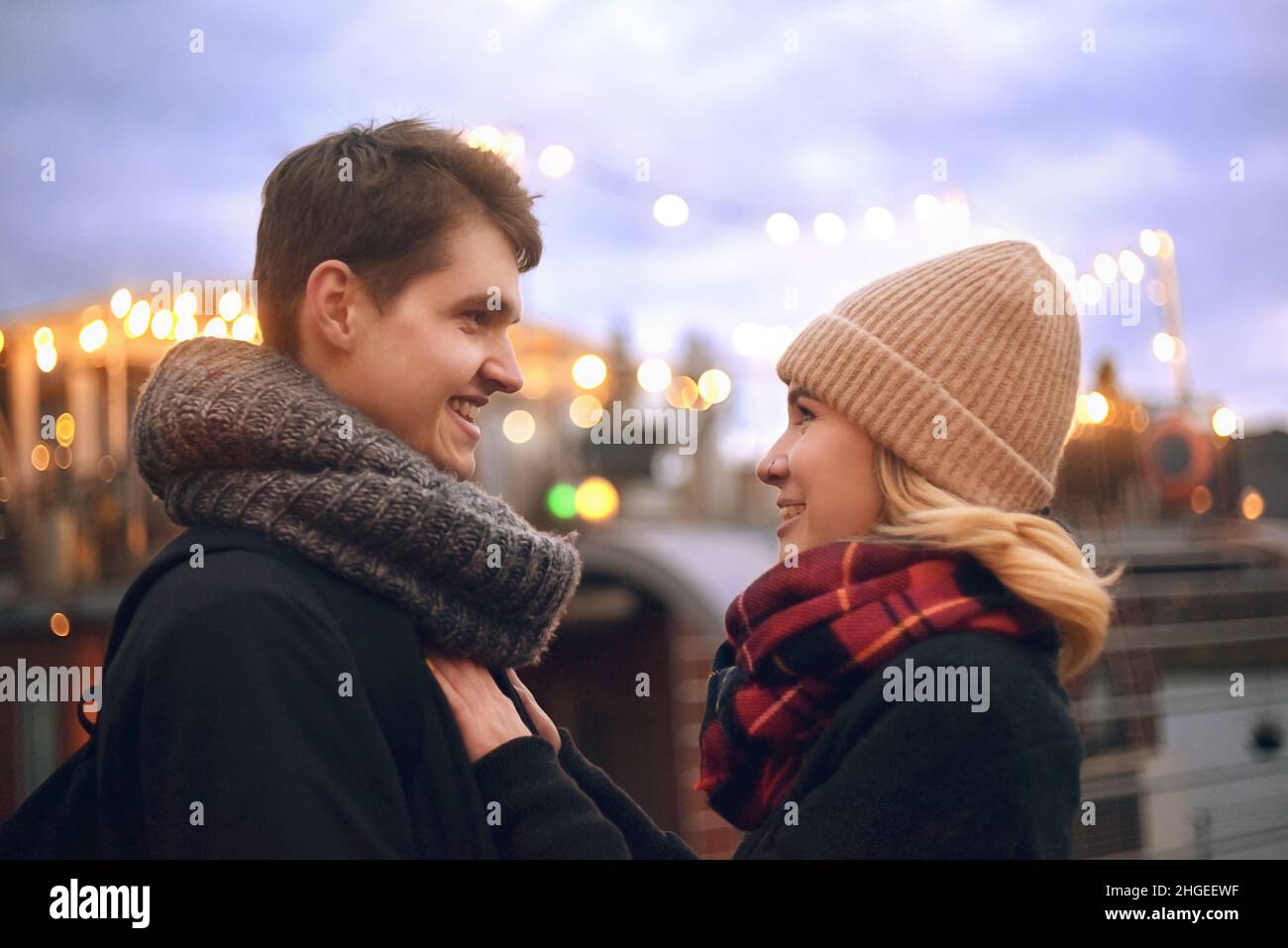 Young couple in love couple travels on St. Valentine's Day. Holidays in Europe. Warm clothes, hat. scarf, nice atmosphere. Flashlights in the backgrou Stock Photo