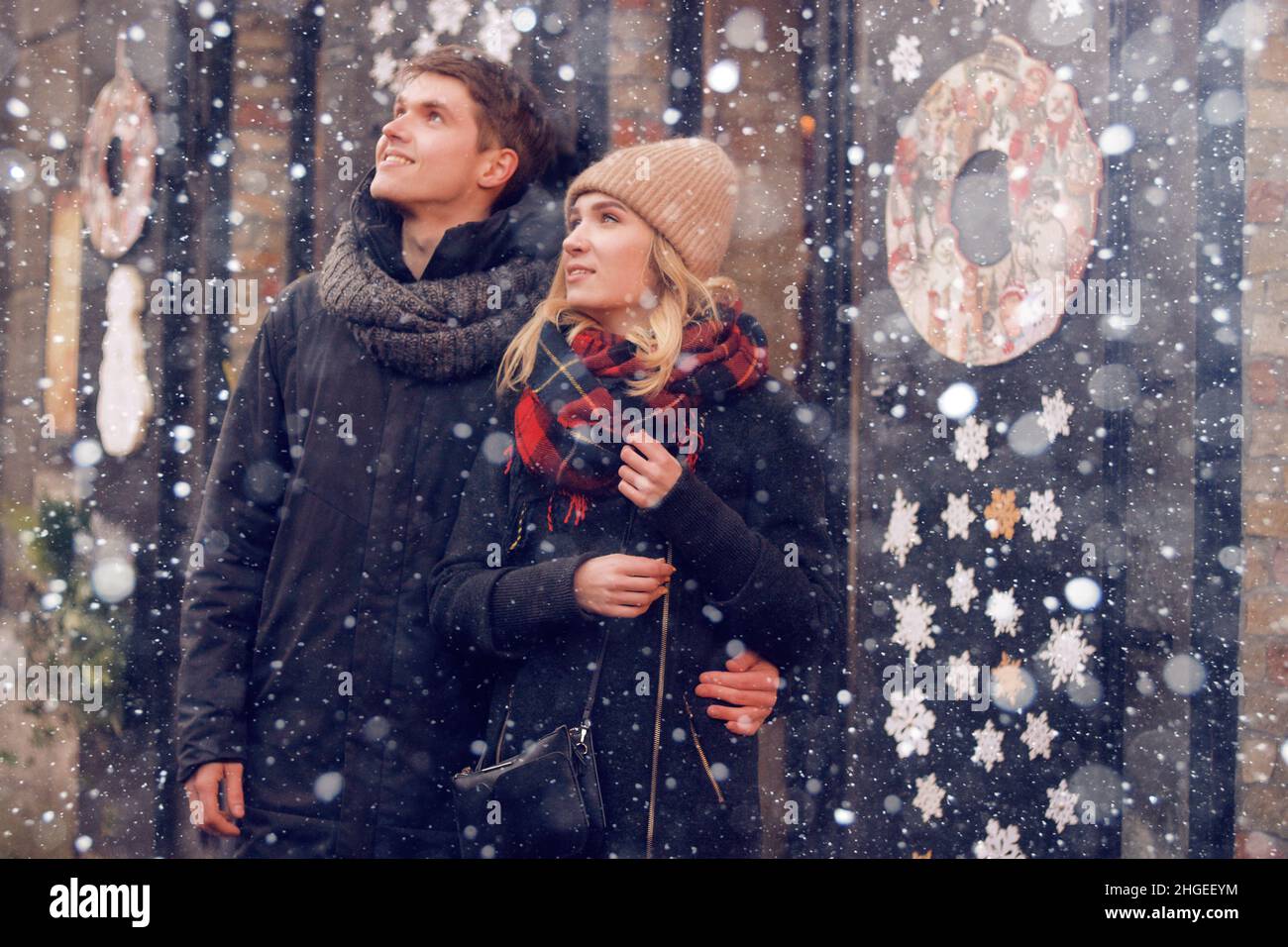 Young couple in love couple travels on St. Valentine's Day. Holidays in Europe. Warm clothes, hat. scarf, nice atmosphere. Winter, snow, magic. Stock Photo