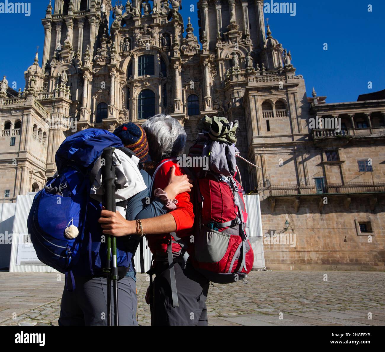 A couple of pilgrims celebrate in front of the cathedral of Santiago that they have reached the end of the journey after walking the Camino de Santiag Stock Photo