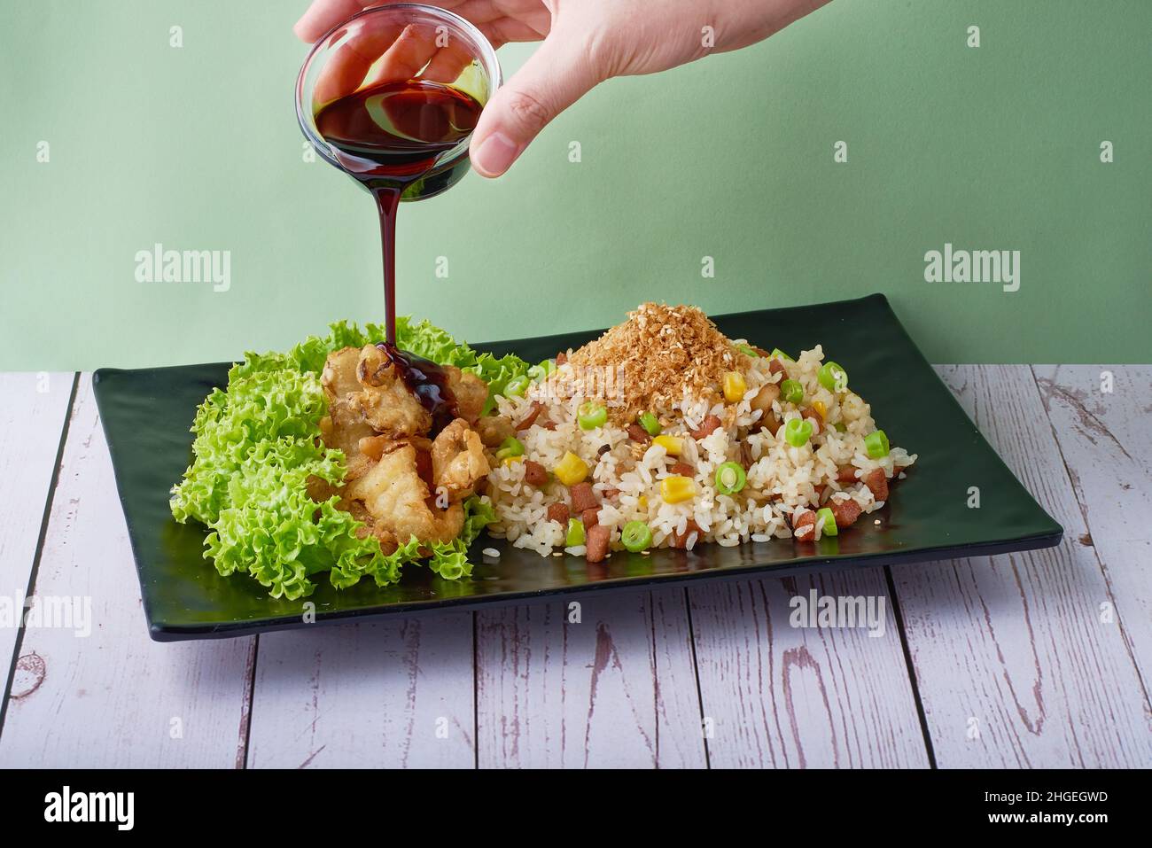Traditional chinese food Fried Rice Yang Zhou with Abalone Mushroom and Teriyaki Sauce in black tray on wood table background Stock Photo