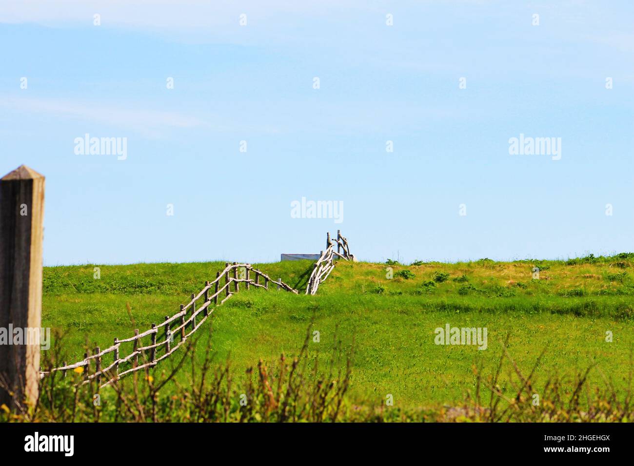 A rustic log fence running up hill through a meadow Stock Photo