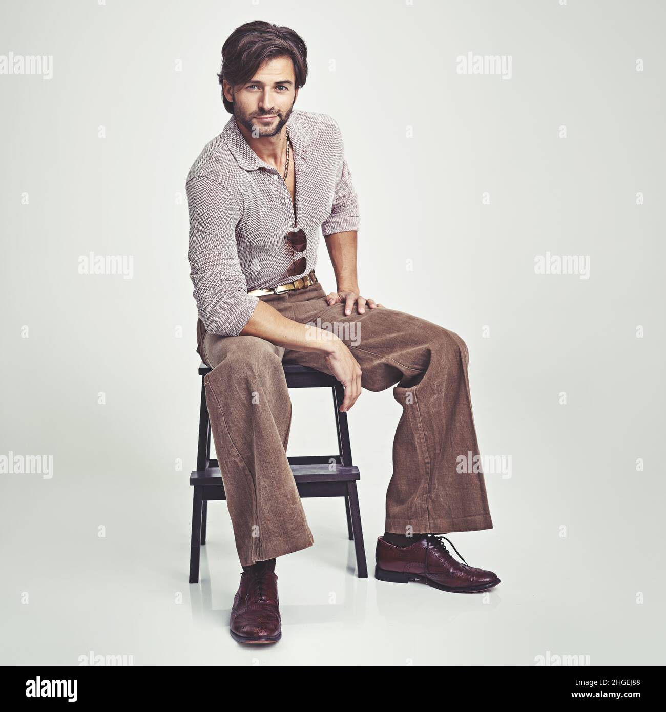 His look is totally retro. A handsome man in 70s style clothing sitting in the studio Stock Photo Alamy
