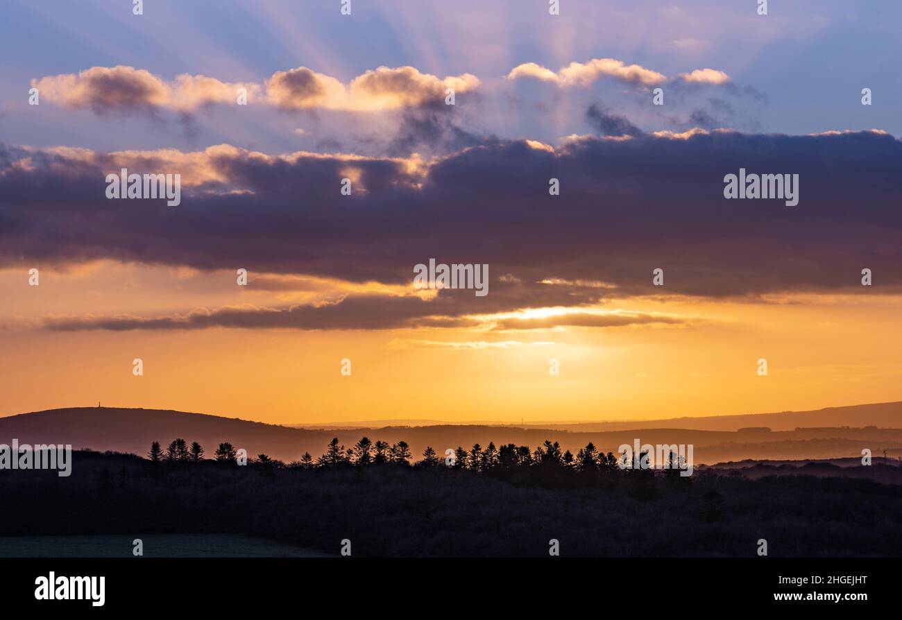 Brentor; Dartmoor National Park, Devon, UK. 20th Jan, 2022. UK Weather: The sky glows orange at sunset as the last of the clouds clear over the horizon and the sun dips over the West Devon countryside. The incoming high pressure is forecast to bring cold and frosty conditions. Credit: PQ/Alamy Live News Stock Photo