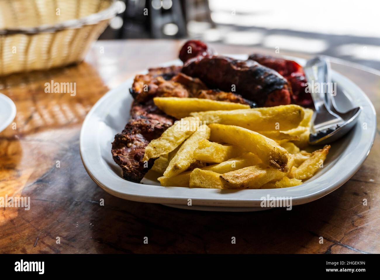 Sausage, veal and pork meat barbecued and served with french fries on Gran Canaria, Spain Stock Photo
