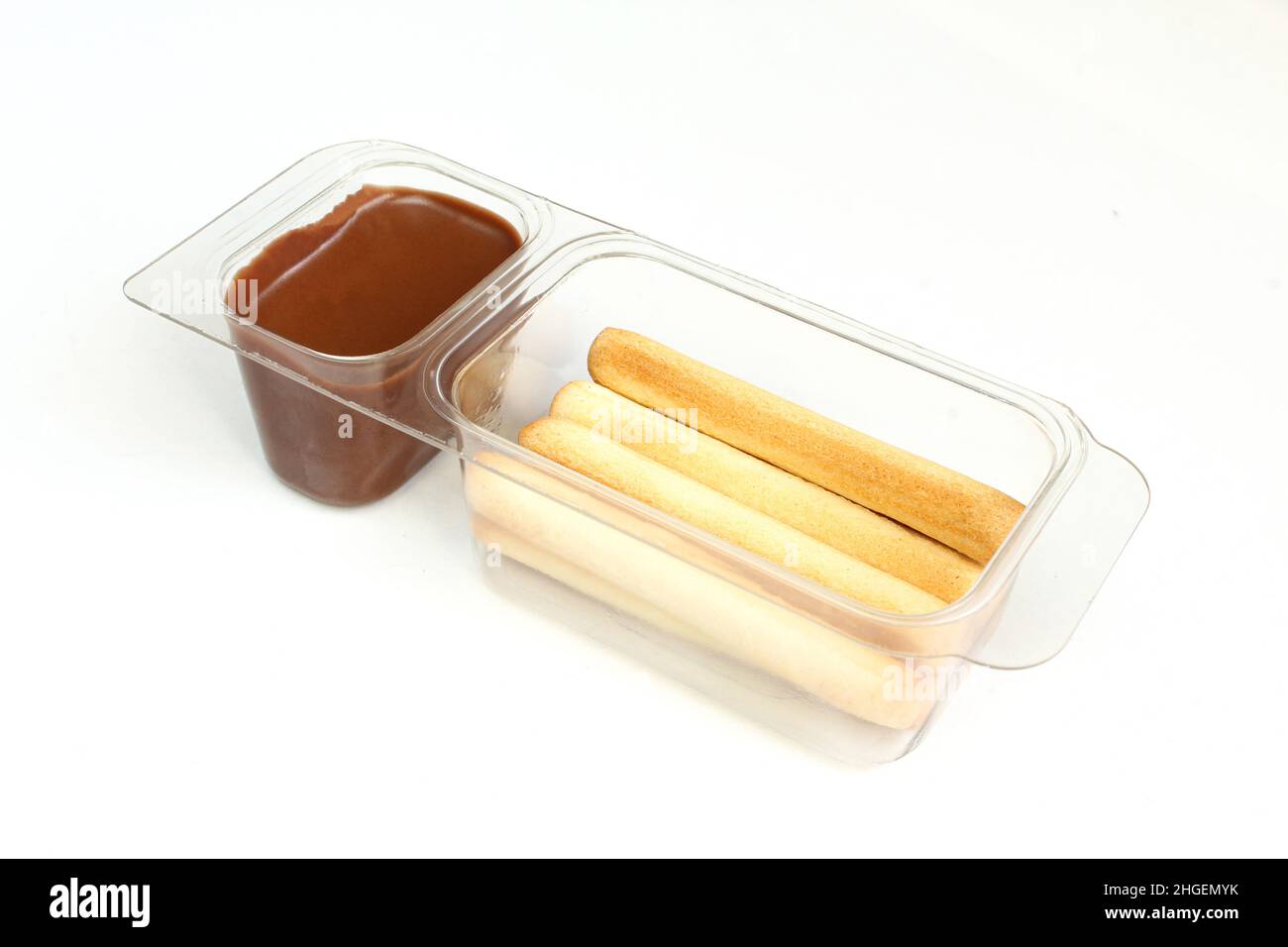 Chocolate cream in transparent plastic container. Sweet wafer sticks and brown hazelnut cream isolated on white Stock Photo