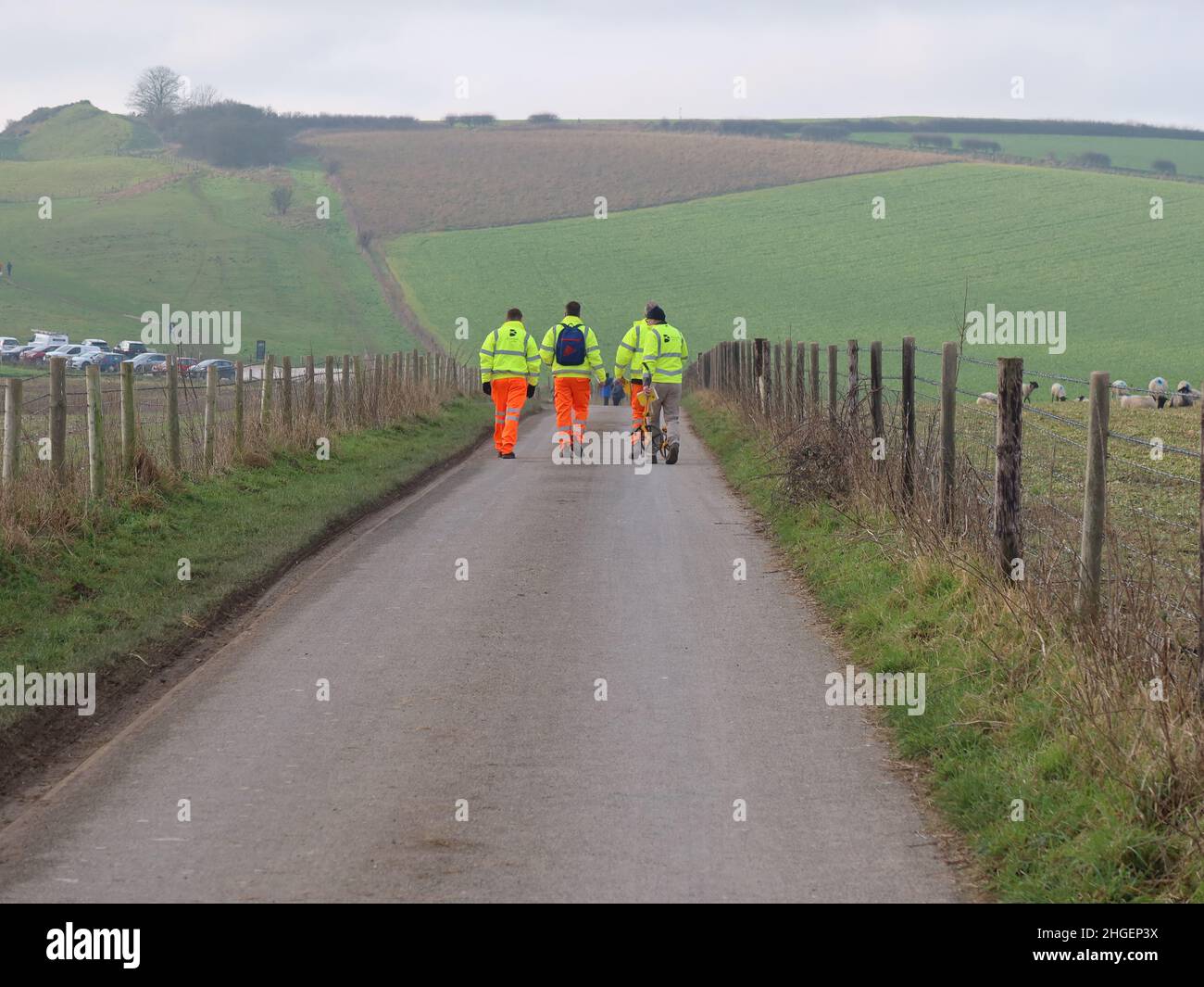 A group of workmen walk along Maiden Castle Road, Dorchester, Dorset in the direction of Maiden Castle. Stock Photo