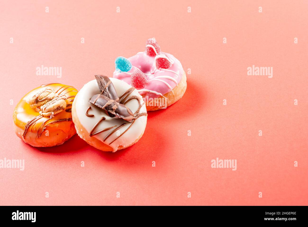 Photograph of three donuts decorated with cookies and jelly beans.The donuts are dipped in strawberry chocolate, dark chocolate and white chocolate.Ph Stock Photo