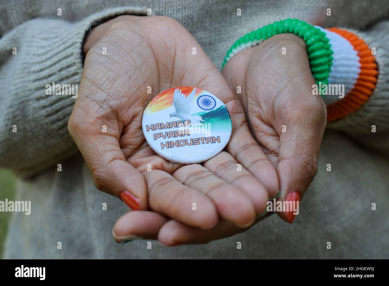 Female holding Indian badge written 'humara pyara hindustan' meaning Our lovely India. Person