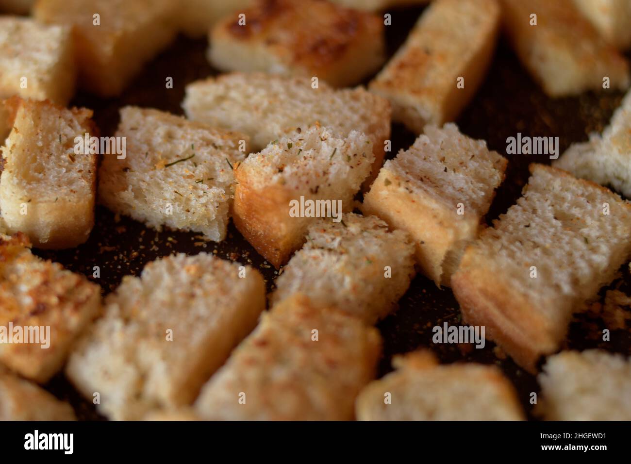 Rusks in the pan. Homemade toasted bread, croutons. Bread in salt, pepper, seasoning, crunchy salad. Stock Photo