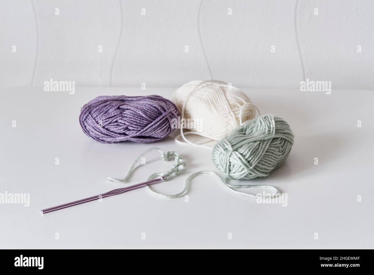 Crochet hook, chain of loops made of light green threads, skeins of