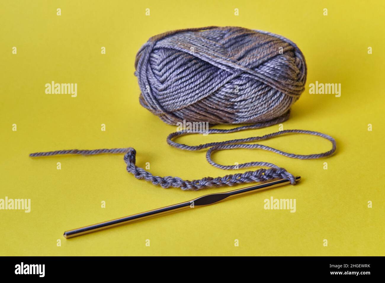 Crochet hook, chain of loops made of violet threads and skein of