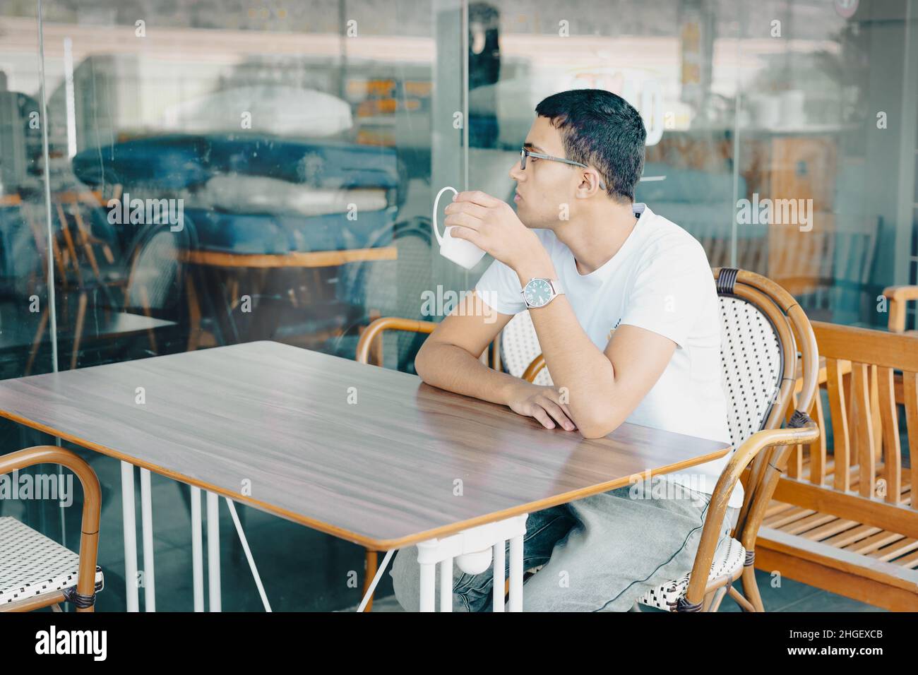 Close-Up Of Young Man Holding Coffe Cup In Cafe. Teenager In A Cafe Drinking Cup Of Tea, Deep In Thought. Stock Photo