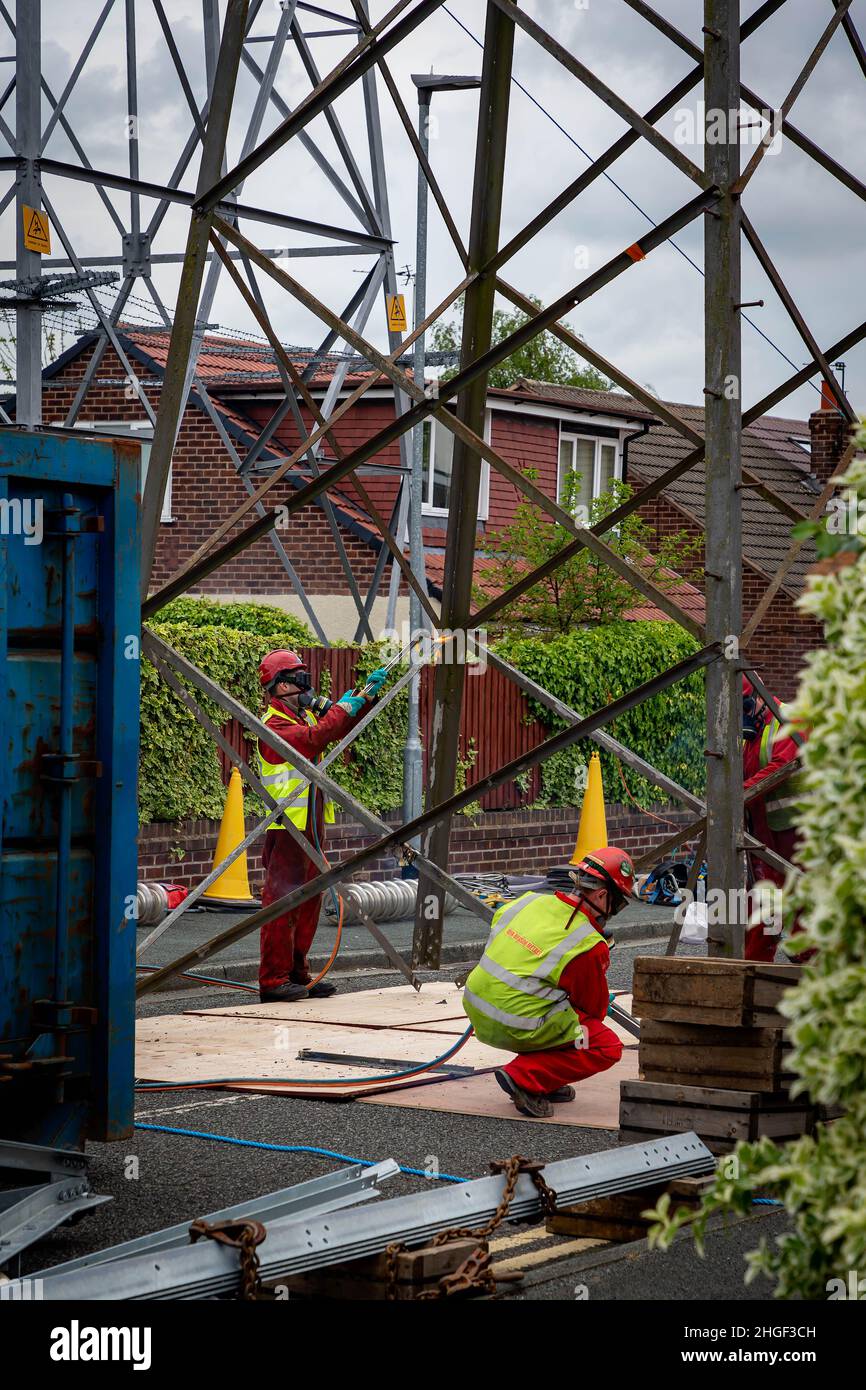 Workmen in PPE use oxy acetylene torches to cut out damaged parts of a