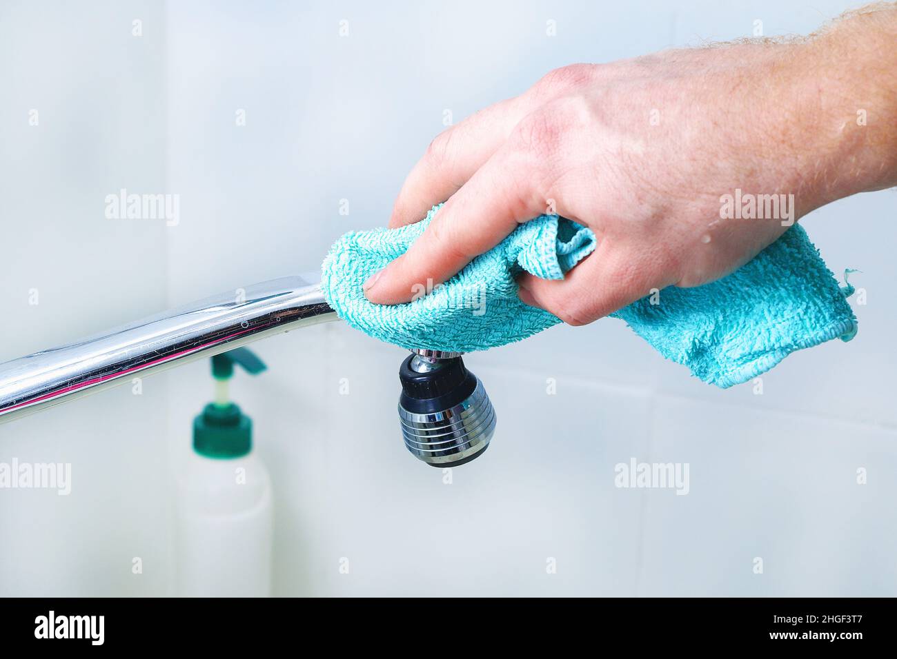 A man wipes a mixer tap, a faucet with a rag. Cleaning of the house ...