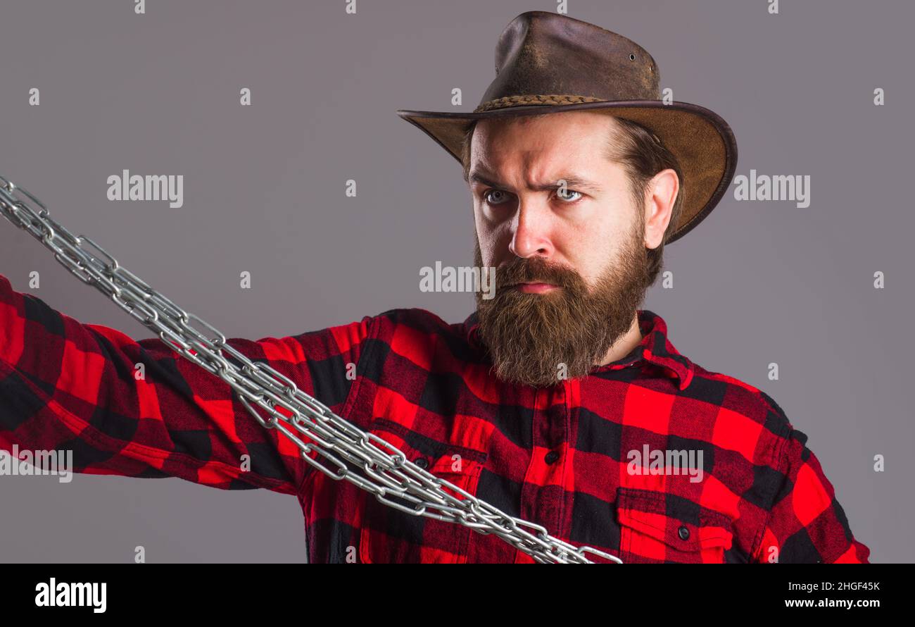Serious man in checkered shirt with metal chain. Bearded male in hat with steel chains. Freedom. Stock Photo