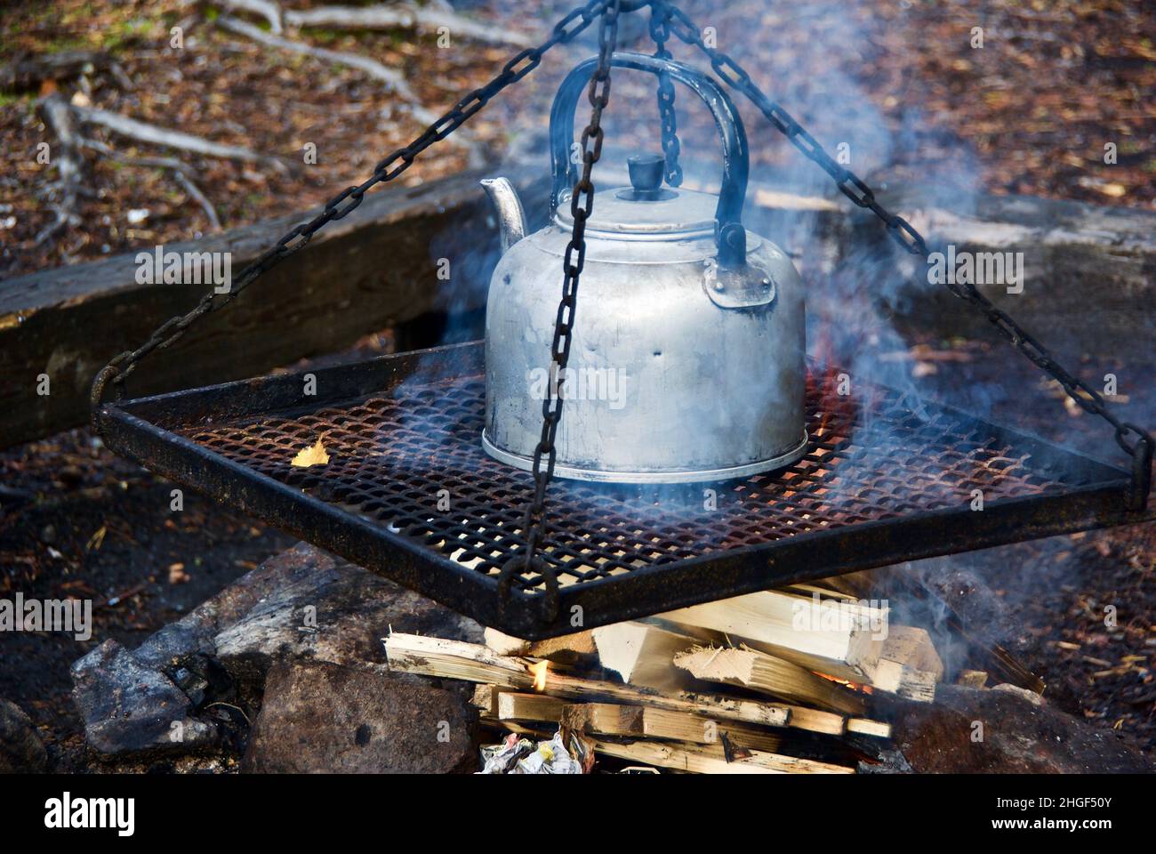 Cooking coffee in old time coffee pot over log fire in the forest in