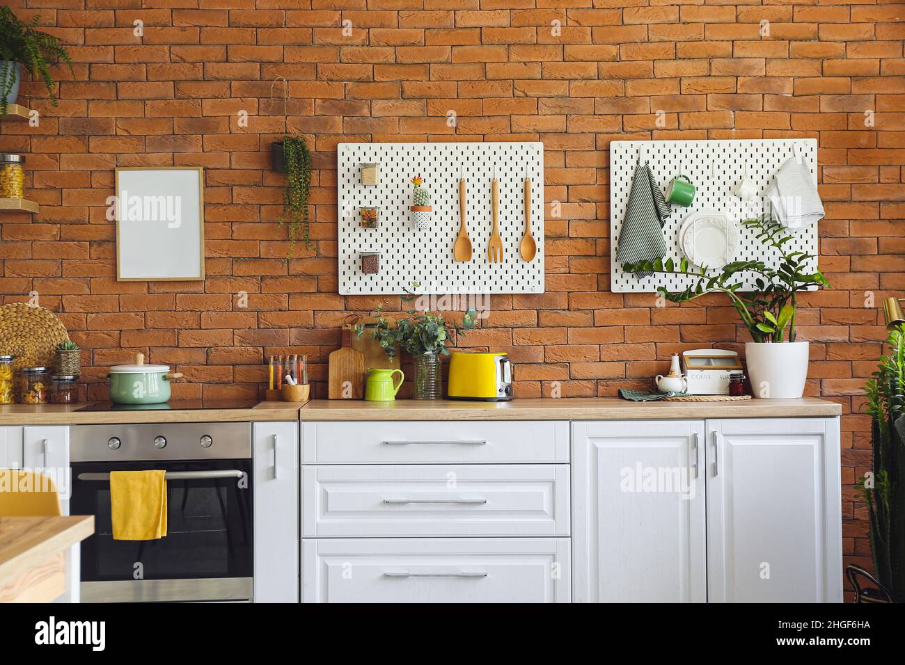 Interior of modern kitchen with white counters, pegboard and brick wall ...