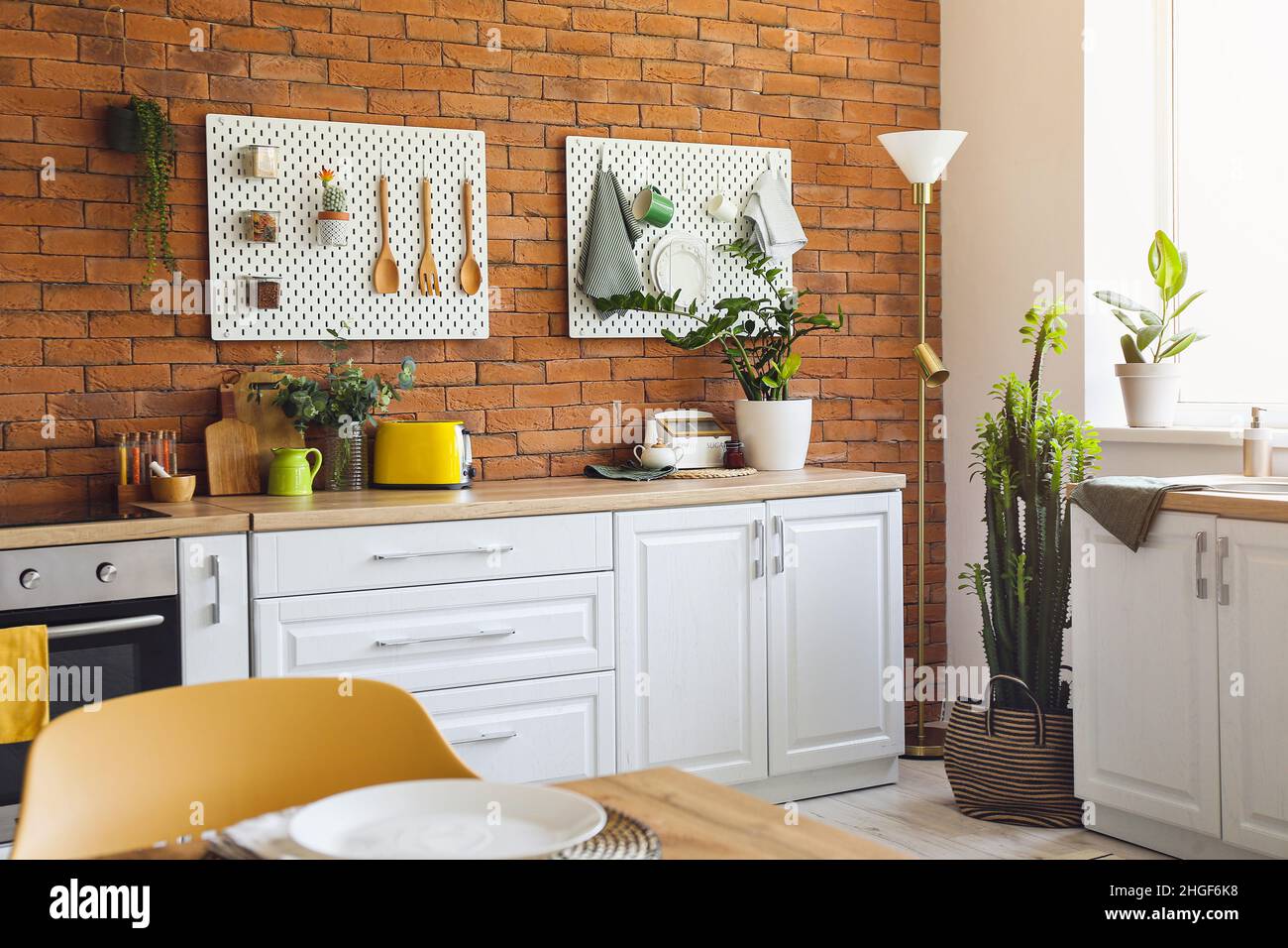 Interior of modern kitchen with white counters, pegboard and brick wall ...