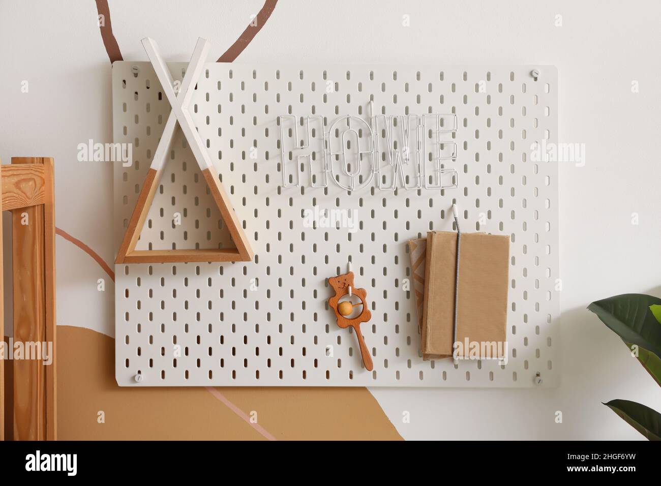 Pegboard with decor, rattle and books hanging on color wall in children's room Stock Photo